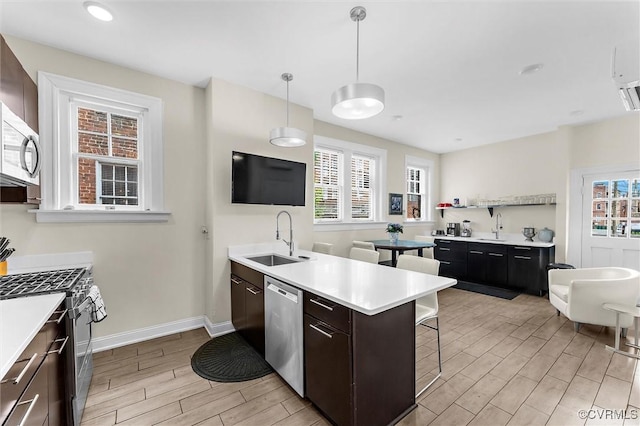 kitchen with a sink, stainless steel appliances, wood finish floors, and a breakfast bar