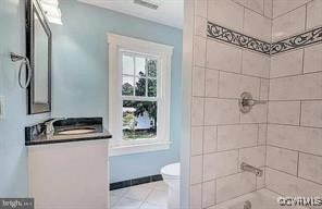 bathroom with vanity, walk in shower, tile patterned floors, and toilet