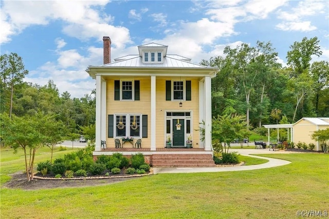 back of house with a chimney, a standing seam roof, metal roof, a porch, and a yard