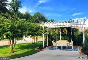view of property's community with a lawn, a pergola, outdoor dining area, and a patio area
