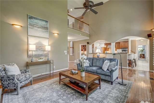 2600 Mulberry Row Rd, Midlothian, VA 23113 - living room featuring arched walkways, a towering ceiling, a ceiling fan, light wood-type flooring, and baseboards
