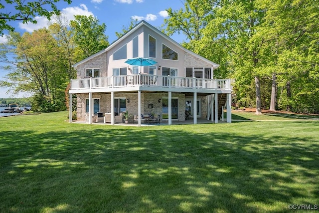 rear view of house with a wooden deck, stone siding, a patio, stairs, and a lawn