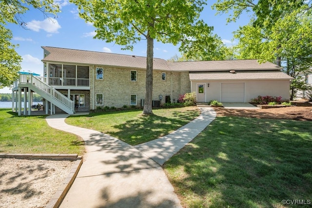 view of front of property featuring a sunroom, a garage, a front lawn, and stairway