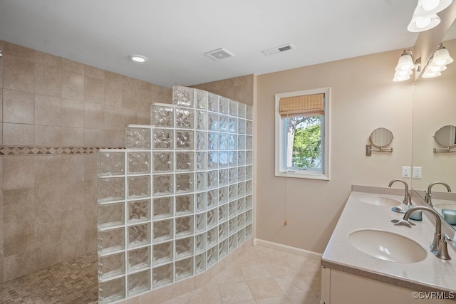 bathroom with visible vents, a sink, and a walk in shower