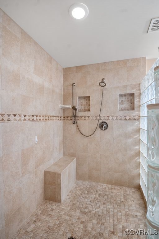 bathroom featuring a tile shower and visible vents