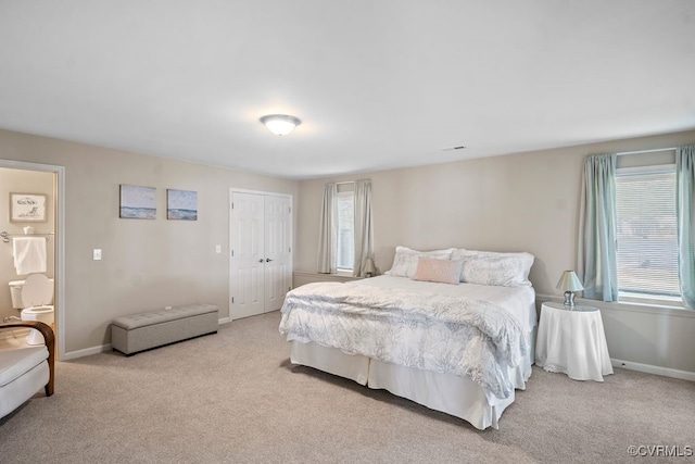 bedroom with baseboards, light colored carpet, and a closet