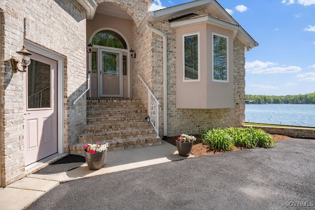 property entrance featuring a water view, stucco siding, and stone siding