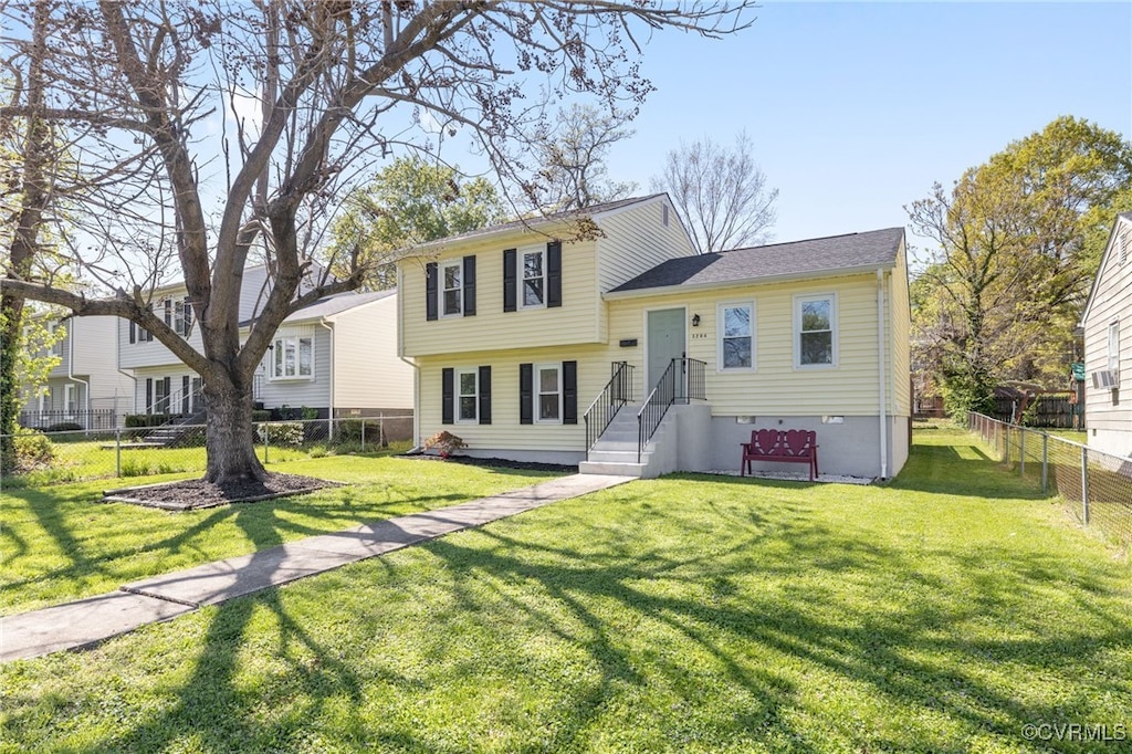 tri-level home with a front lawn and fence private yard
