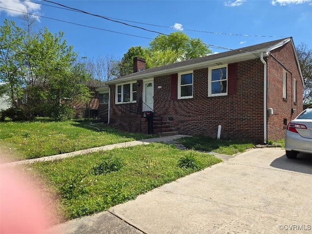view of front of property with a chimney, a front lawn, concrete driveway, and brick siding