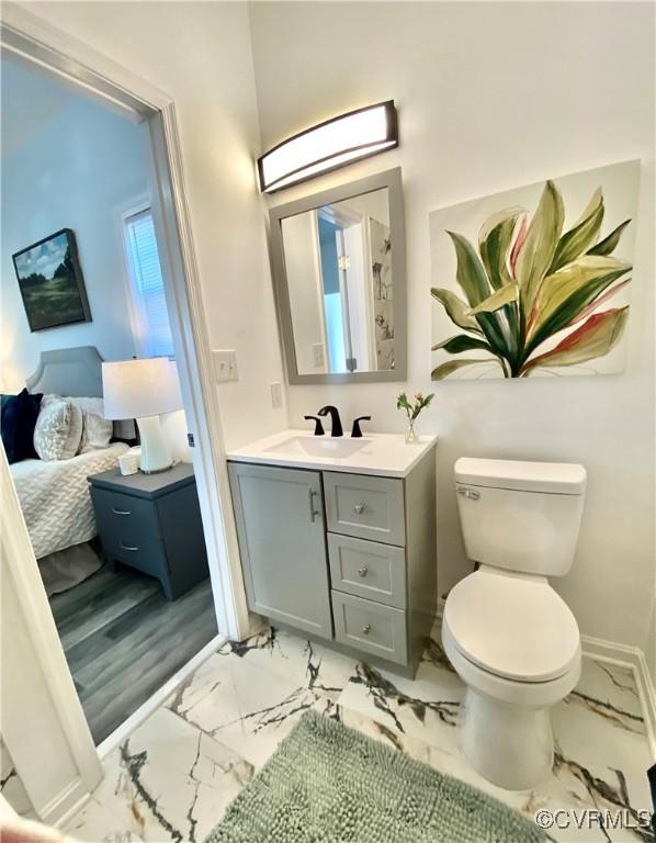 bathroom featuring vanity, marble finish floor, baseboards, and toilet