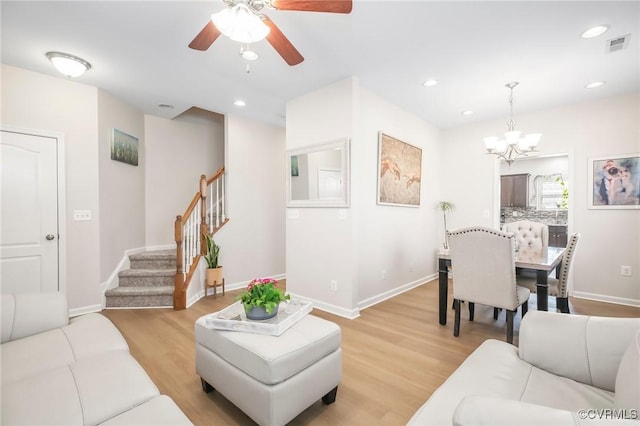 17318 Library Blvd, Ruther Glen, VA 22546 - living room featuring visible vents, baseboards, light wood finished floors, stairway, and ceiling fan with notable chandelier