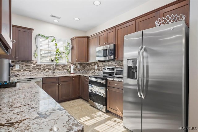 17318 Library Blvd, Ruther Glen, VA 22546 - kitchen featuring visible vents, light stone counters, a sink, stainless steel appliances, and decorative backsplash