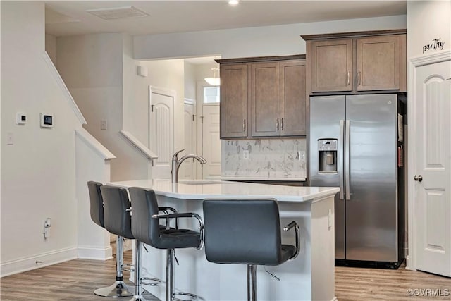 6177 Bowline Ln, Richmond, VA 23234 - kitchen featuring stainless steel fridge with ice dispenser, light wood-style floors, an island with sink, and light countertops