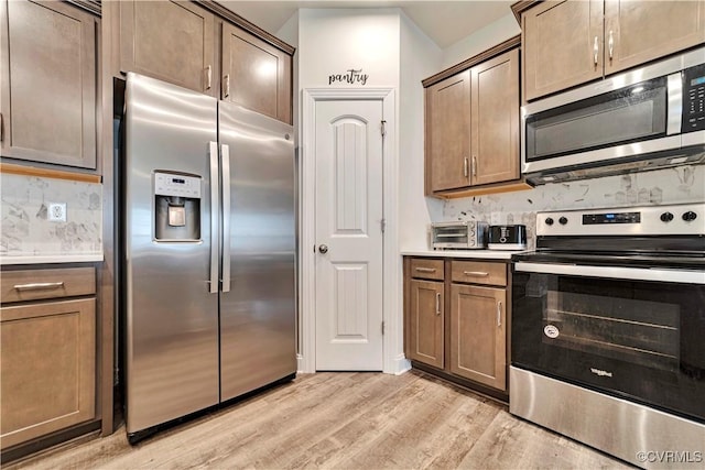 6177 Bowline Ln, Richmond, VA 23234 - kitchen featuring stainless steel appliances, light wood finished floors, light countertops, and decorative backsplash