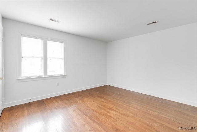 spare room with light wood finished floors, baseboards, and visible vents