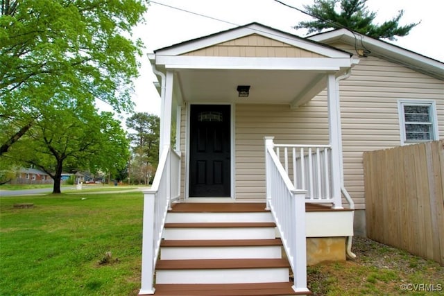 doorway to property with fence and a yard