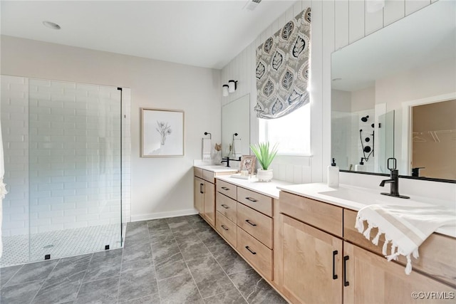 bathroom featuring double vanity, baseboards, a sink, and a stall shower