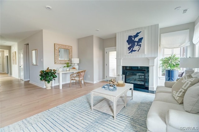 living room with baseboards, plenty of natural light, light wood-type flooring, and visible vents
