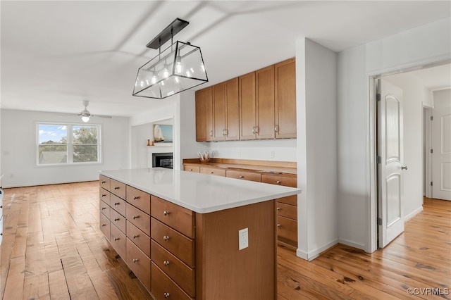 kitchen with brown cabinets, a center island, light wood-style floors, and a ceiling fan