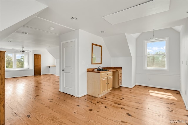 bonus room with vaulted ceiling, light wood finished floors, baseboards, and a sink