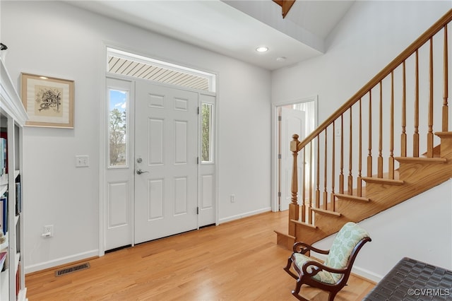entrance foyer with baseboards, visible vents, light wood-style floors, and stairway