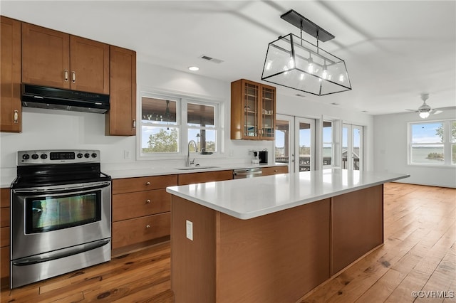 kitchen featuring visible vents, a sink, under cabinet range hood, brown cabinets, and stainless steel appliances