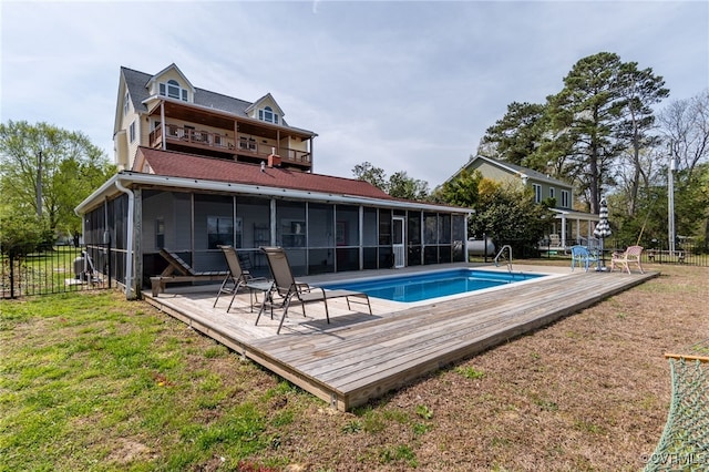 back of property with a sunroom, fence, a fenced in pool, and a deck