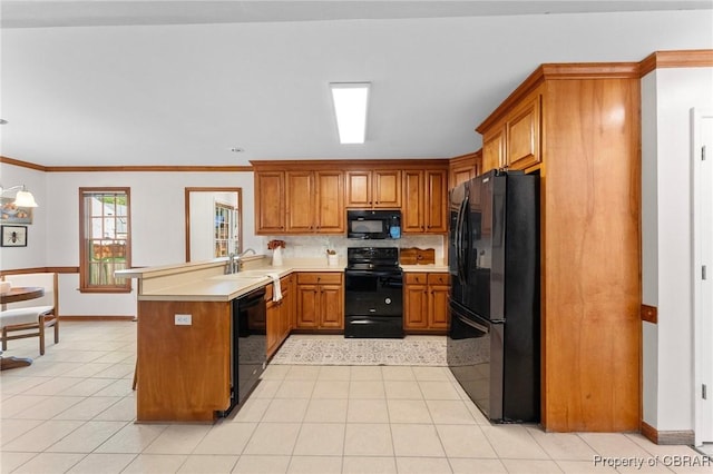 kitchen with baseboards, a peninsula, light countertops, brown cabinetry, and black appliances