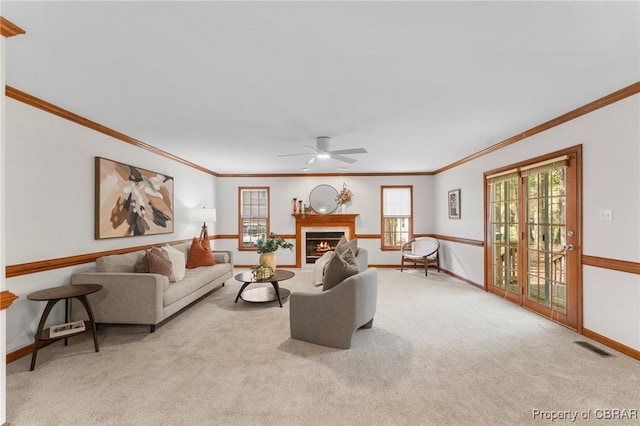 carpeted living area featuring visible vents, crown molding, baseboards, and a ceiling fan