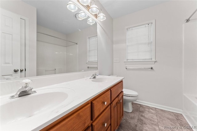 full bath featuring a sink, baseboards, double vanity, and toilet