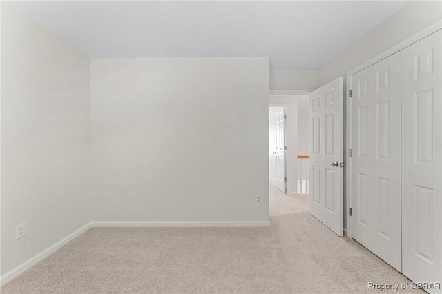 unfurnished room with baseboards and light colored carpet