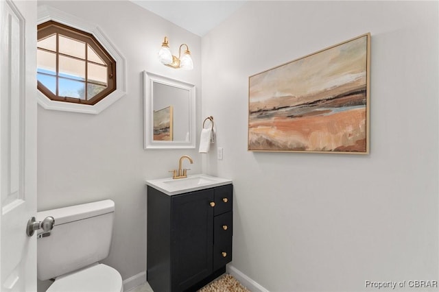 half bath with toilet, vanity, and baseboards