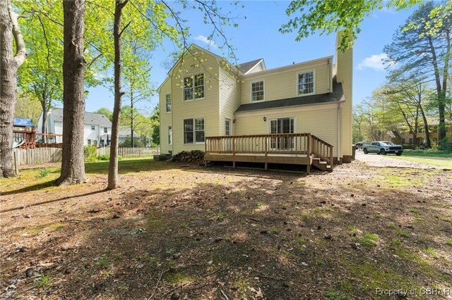 back of house with a deck, a chimney, and fence
