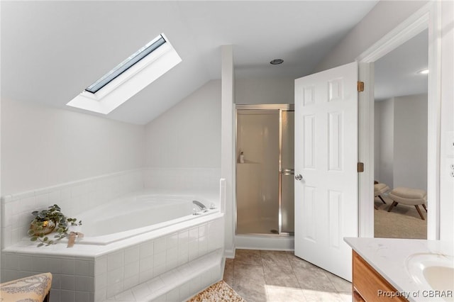 bathroom with vaulted ceiling with skylight, vanity, a garden tub, and a stall shower