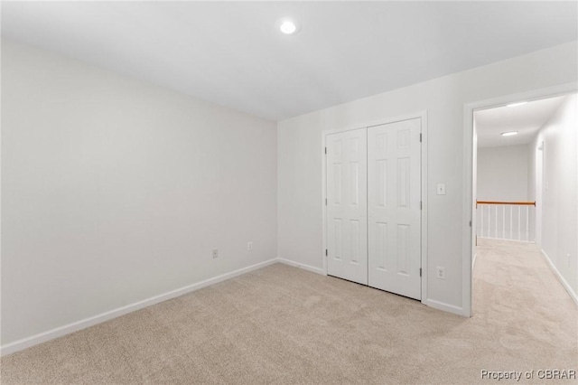 unfurnished bedroom with carpet floors, baseboards, recessed lighting, and a closet