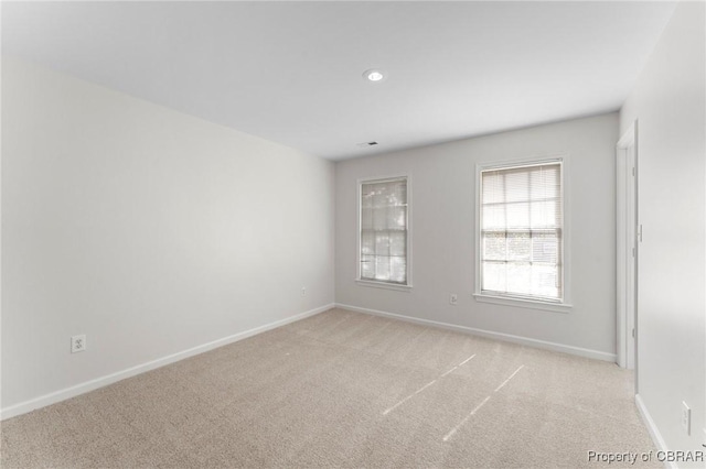 spare room featuring light carpet, recessed lighting, and baseboards