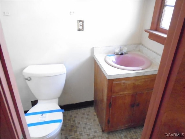 bathroom featuring toilet, vanity, and baseboards