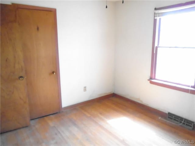 spare room featuring light wood finished floors, baseboards, and visible vents