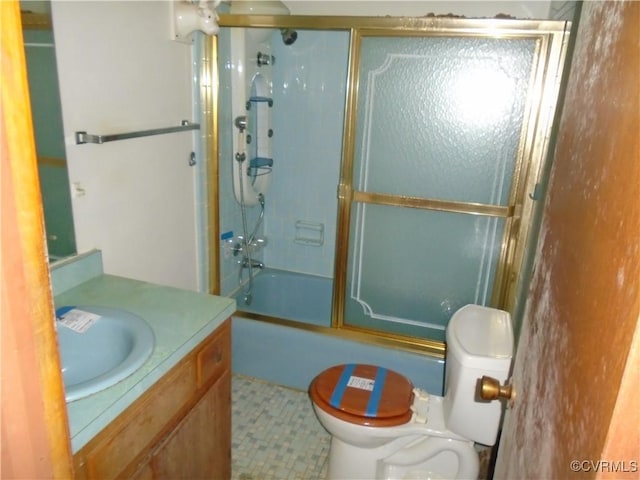 bathroom featuring toilet, vanity, and combined bath / shower with glass door