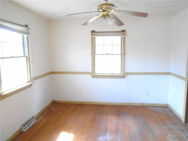 spare room featuring visible vents, ceiling fan, wood finished floors, and baseboards