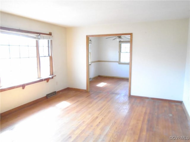 empty room featuring wood finished floors, baseboards, and visible vents