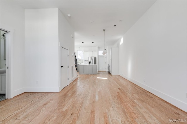 unfurnished living room featuring light wood finished floors and baseboards