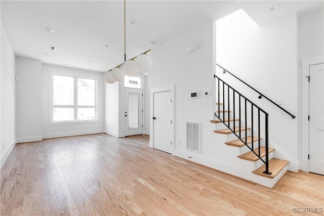 interior space with stairway, visible vents, baseboards, and wood finished floors