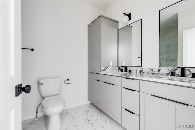 bathroom featuring toilet, marble finish floor, a sink, double vanity, and baseboards