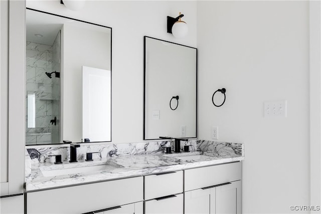 bathroom featuring double vanity, a sink, and a marble finish shower