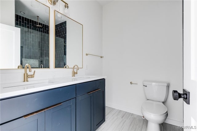 bathroom featuring toilet, a stall shower, a sink, and baseboards