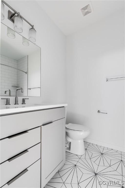 bathroom with vanity, visible vents, toilet, tile patterned floors, and baseboards
