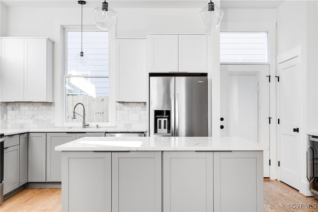 kitchen with gray cabinets, tasteful backsplash, stainless steel fridge with ice dispenser, and light countertops