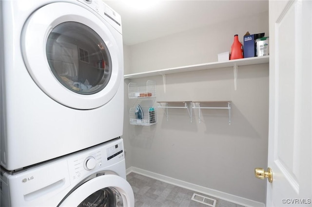 clothes washing area featuring baseboards, laundry area, stacked washer and dryer, and visible vents