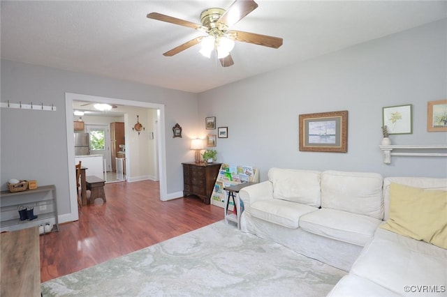 living room featuring baseboards, a ceiling fan, and wood finished floors